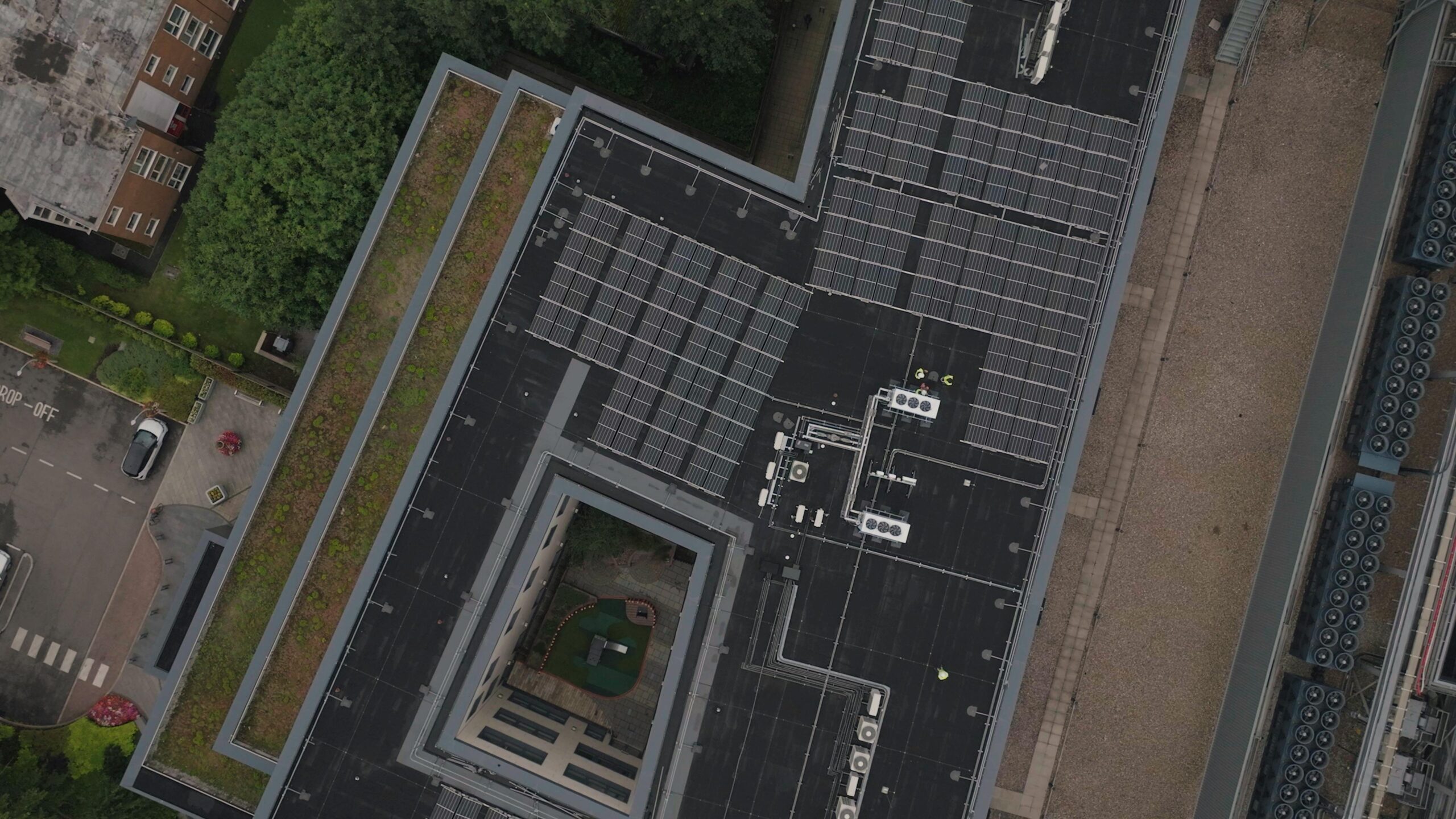 Services High-angle view of urban rooftop featuring solar panels and greenery.